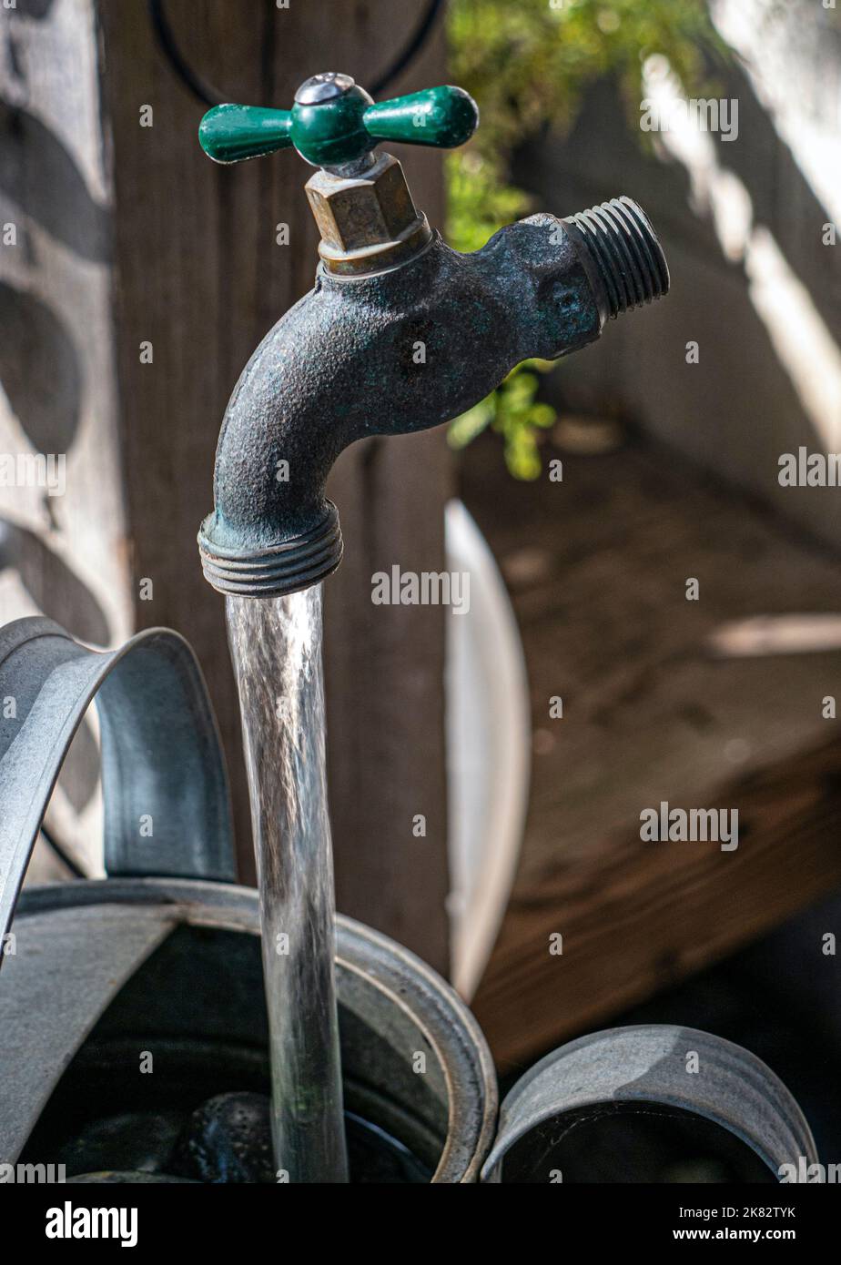 Magic Garden Tap feature water apparently running novelty trick, water running into stone filled water bucket from water tap appearing to float in air Stock Photo
