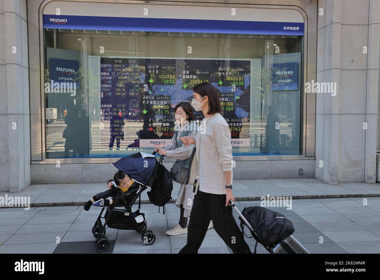 Pedestrians Walk By An Electronic Board Which Shows Economic Data In pedestrians-walk-by-an-electronic-board-which-shows-economic-data-in