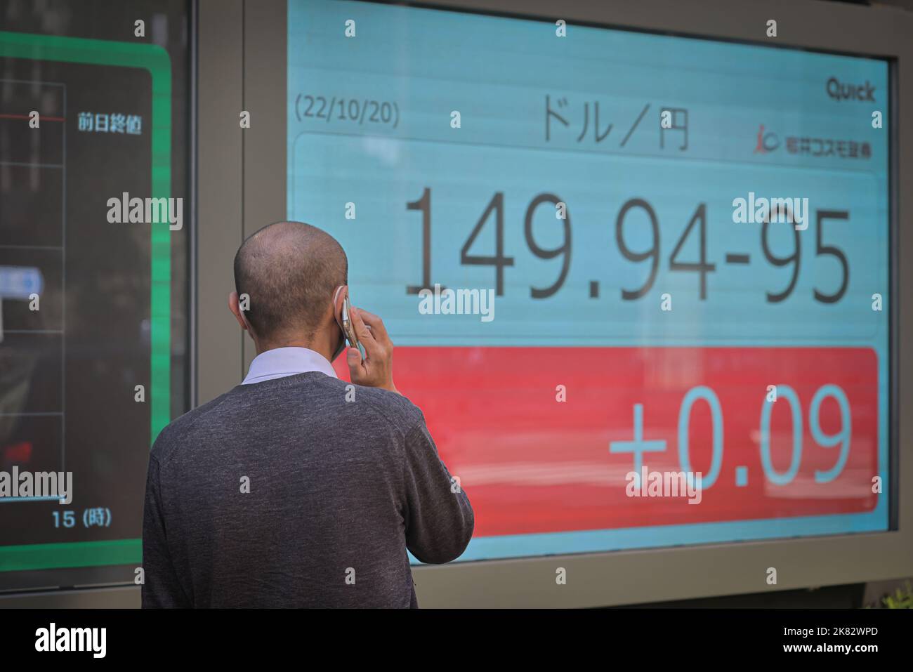 Man Talks On The Phone While Looking At An Electronic Board Which Shows man-talks-on-the-phone-while-looking-at-an-electronic-board-which-shows