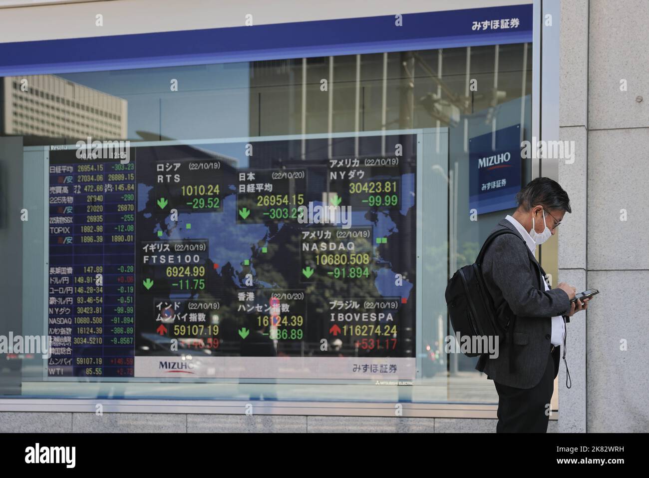 a-man-looks-at-his-phone-while-standing-close-to-an-electronic-board