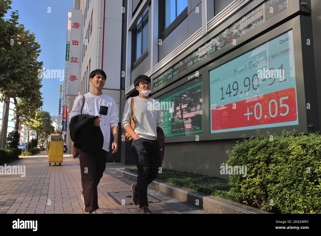 pedestrians-walk-by-an-electronic-board-which-shows-economic-data-in