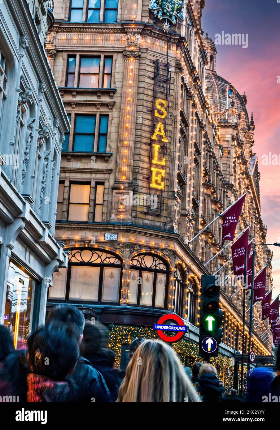 SALES HARRODS SALE SIGN CROWDS Harrods department store at dusk with
