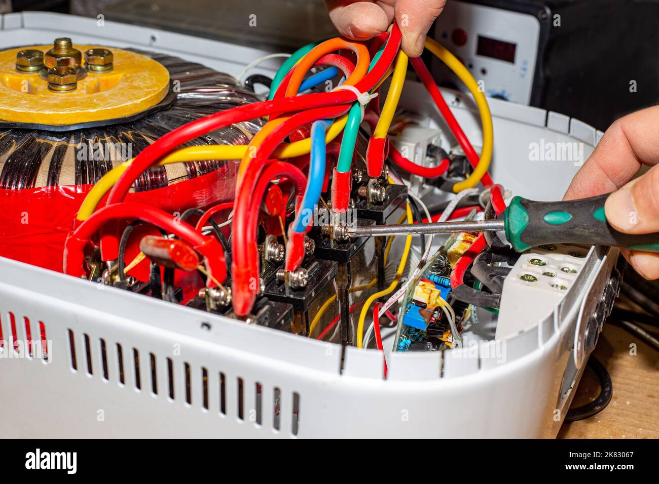 Voltage stabilizer repair. An electrician unscrews the power wires of