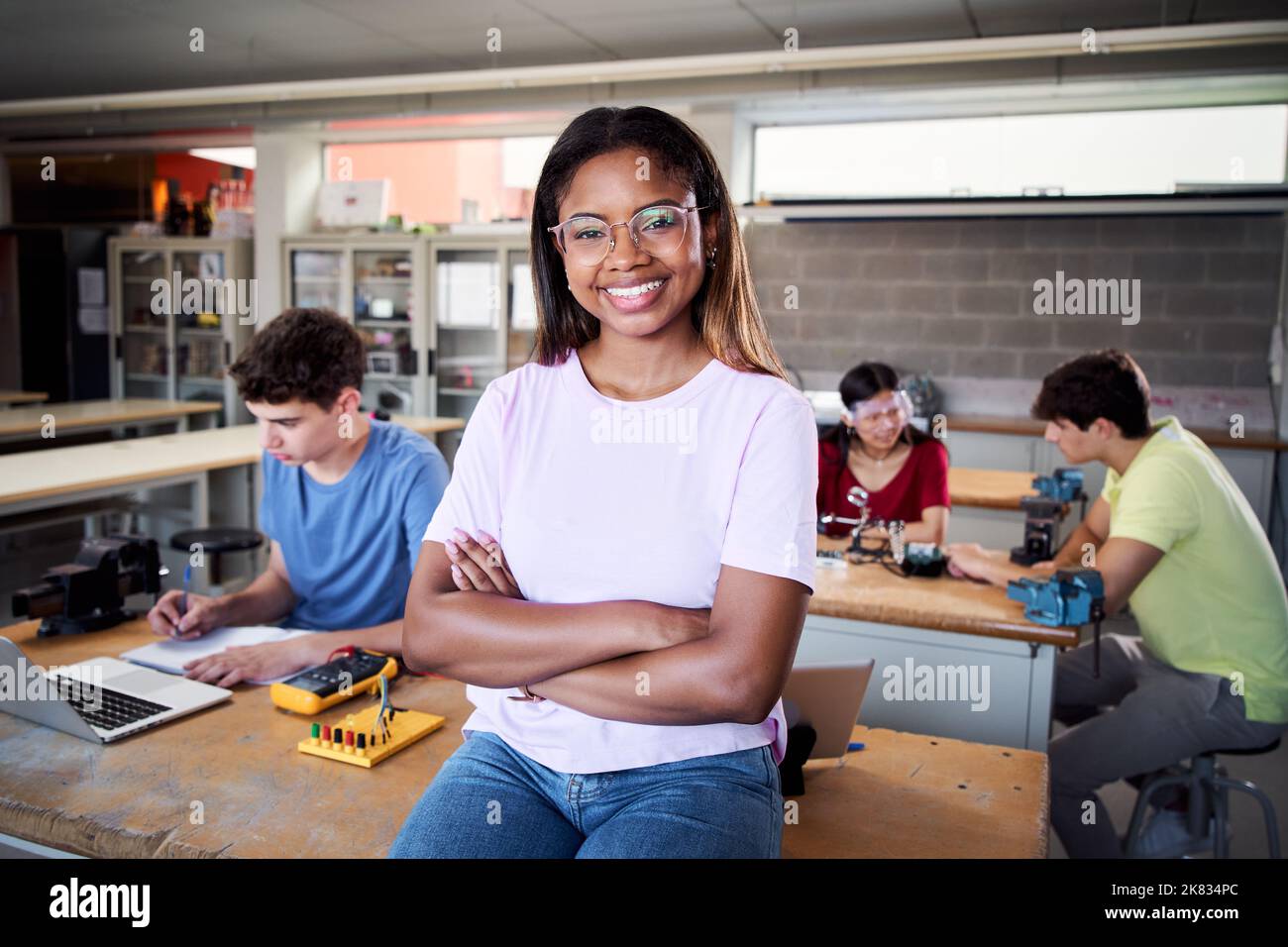 Portrait of a latina in the classroom looking at the camera with her arms crossed. Young students doing technical vocational practice in electronic Stock Photo