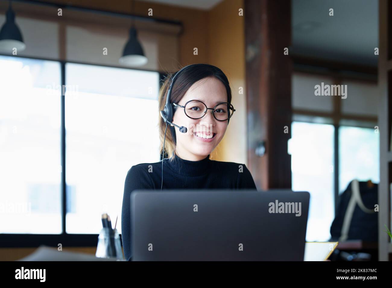 Portrait of a teenage Asian woman wearing glasses using computer laptop