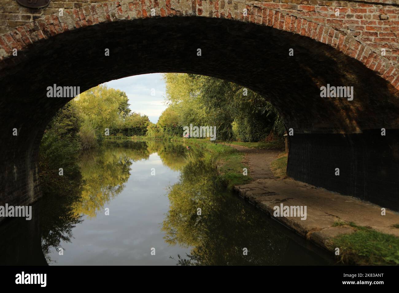 Two people fishing beyond a bridge on the Grand Union Canal, Buckinghamshire, United Kingdom Stock Photo