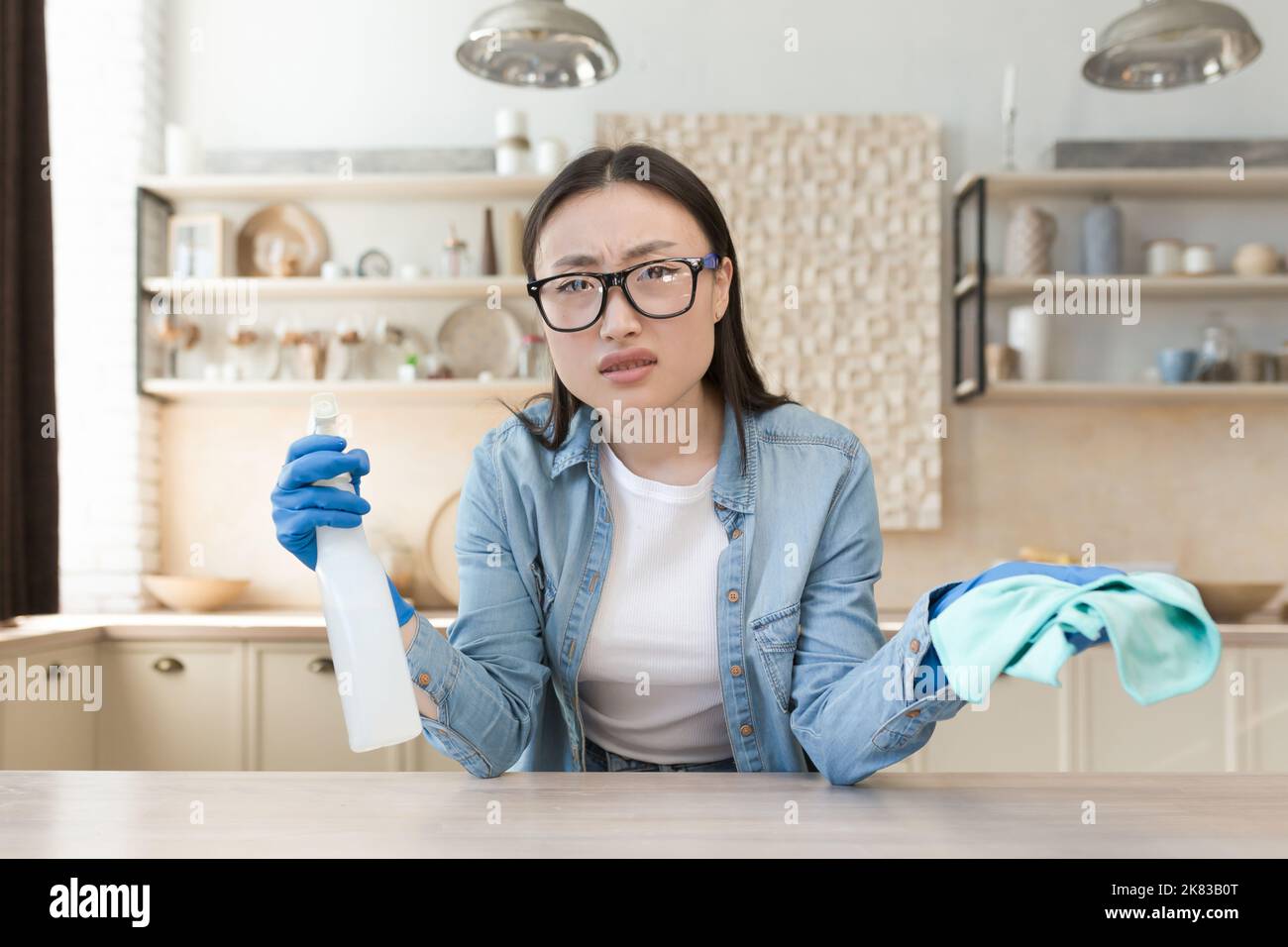 Tired young beautiful Asian woman cleaning at home. Wipes the table ...