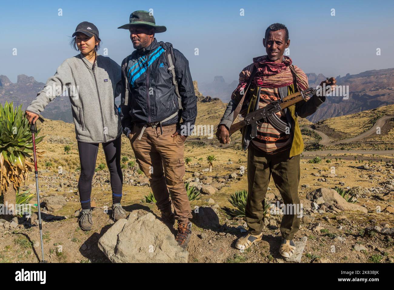 SIMIEN MOUNTAINS, ETHIOPIA - MARCH 17, 2019: Tourist, local tour guide and an armed scout guarding tourists in Simien mountains, Ethiopia Stock Photo