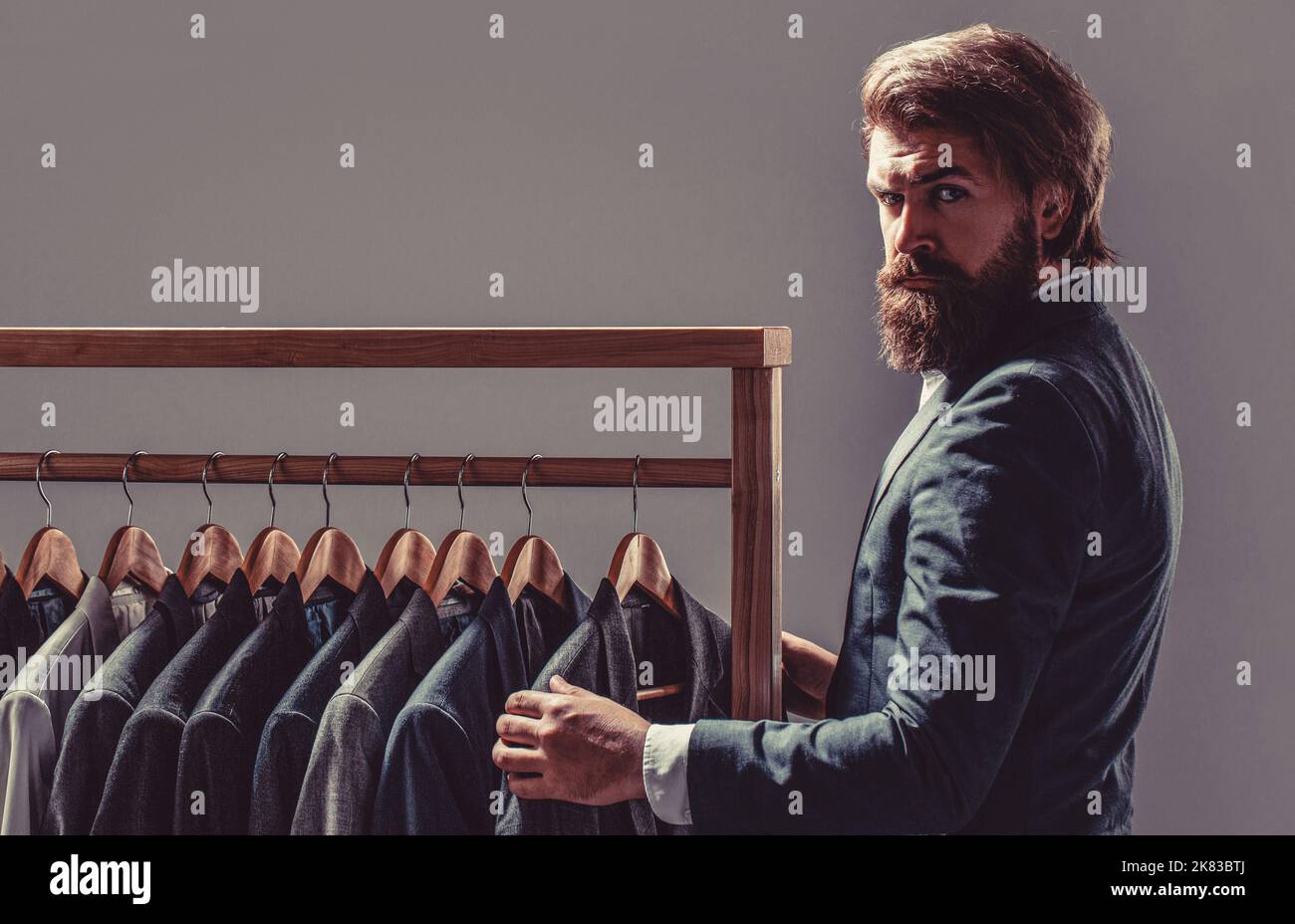 Elegant man's suits hanging in a row. Luxury mens classic suits on rack in elegant men's boutique Stock Photo