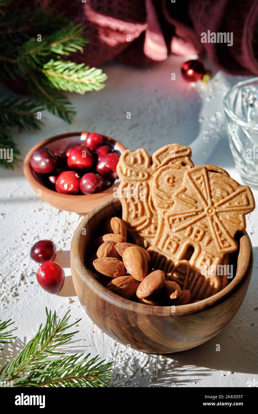 Speculoos or Spekulatius, Christmas biscuits, with cranberry berries, almonds on a table with kitchen towel and fir twigs. Traditional German sweets Stock Photo