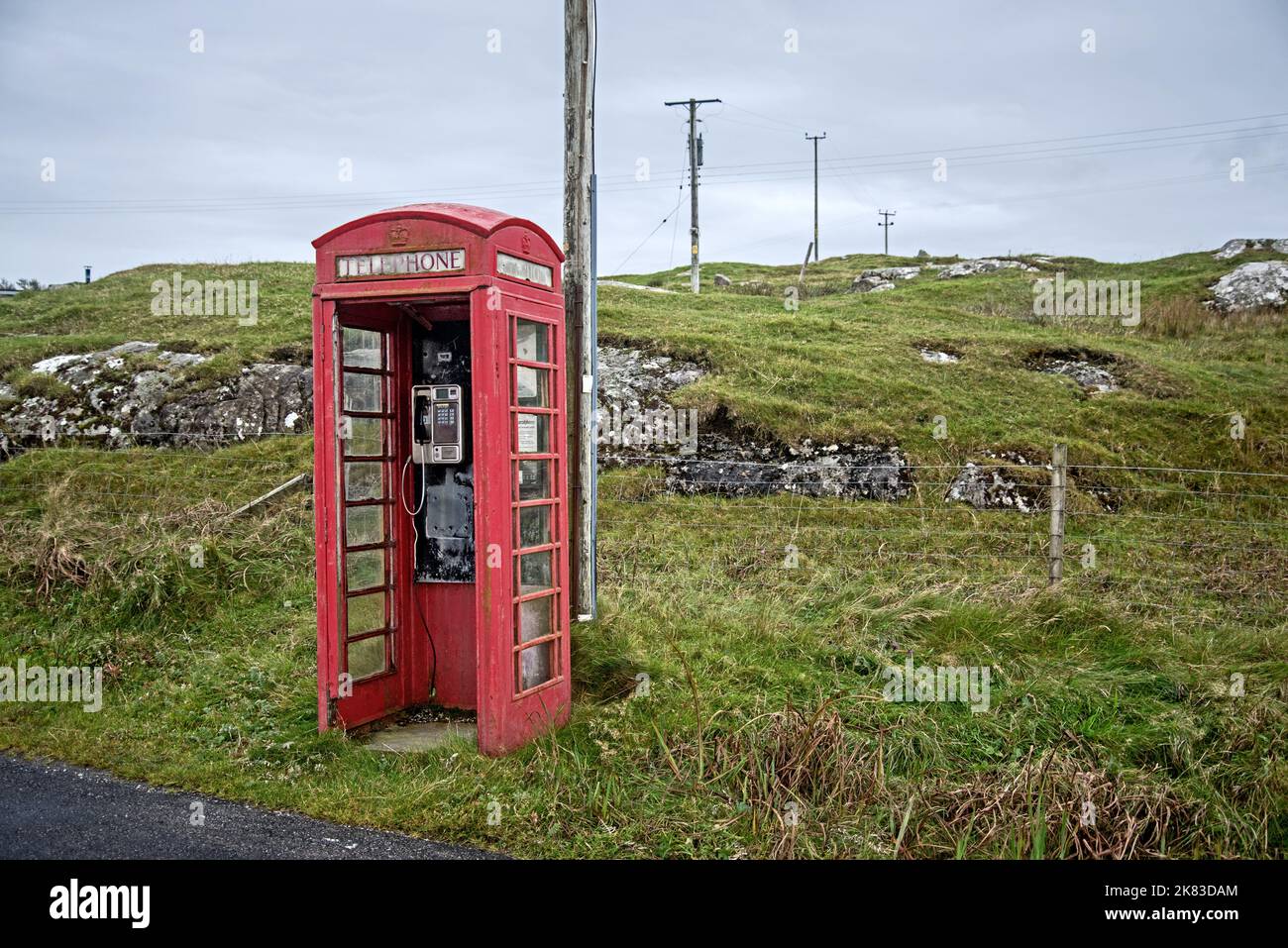 Red telephone box, without door due to strong winds on the Island of Barra in the Outer Hebrides, Scotland, UK. Stock Photo