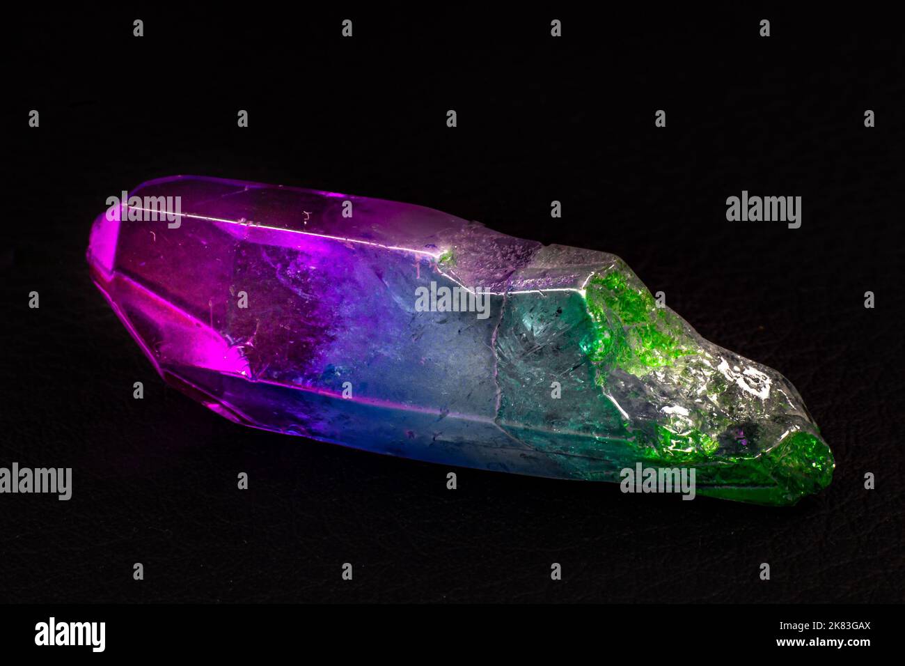 Vibrant colorful Cocktail aura quartz point macro isolated on a black surface. Colorful, pink, blue, white, purple and green man-enhanced Stock Photo