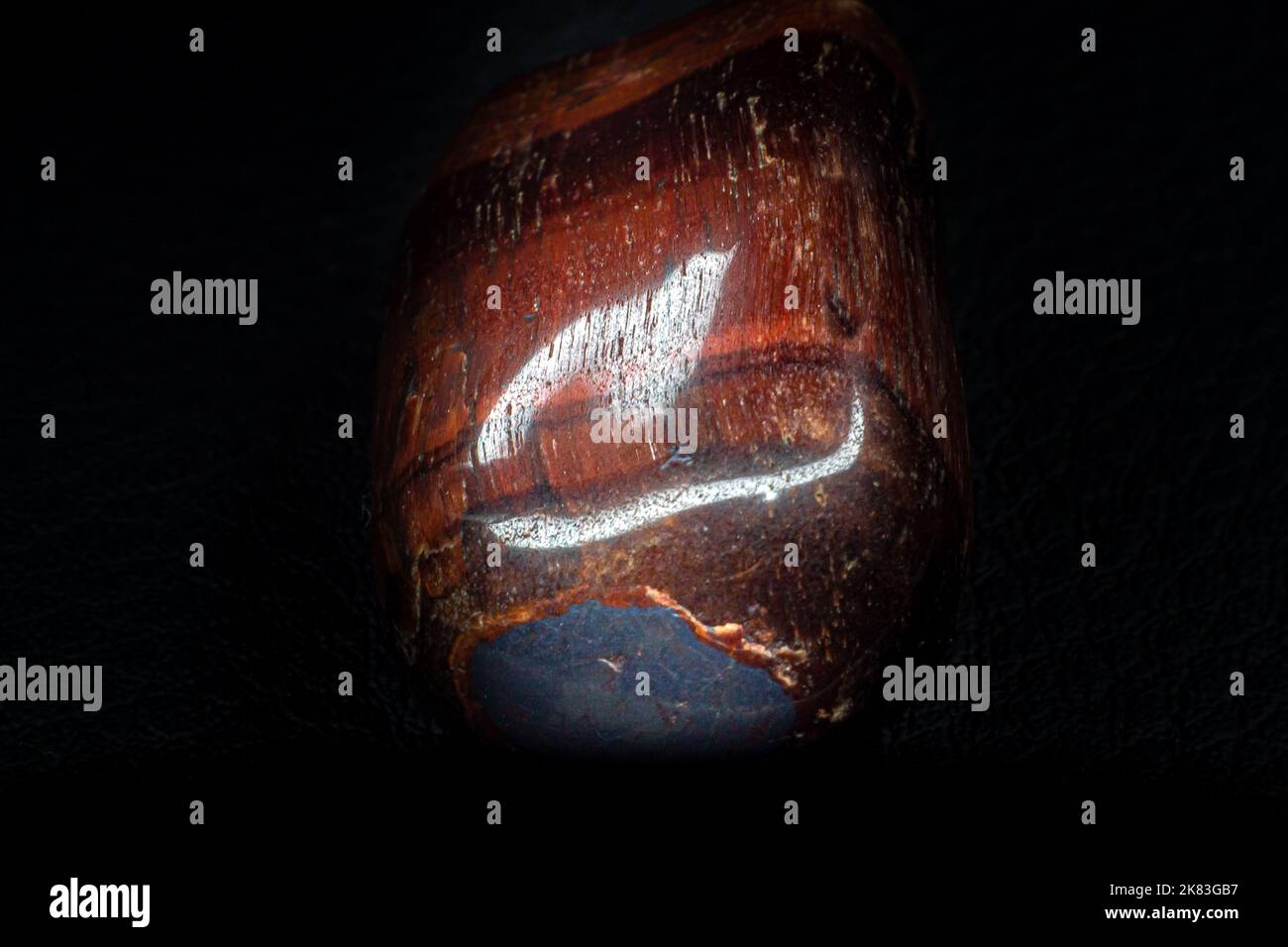 https://c8.alamy.com/comp/2K83GB7/brown-and-red-tigers-eye-dragons-eye-tumbled-rock-crystal-smooth-and-shiny-isolated-on-a-black-background-surface-copy-space-2K83GB7.jpg