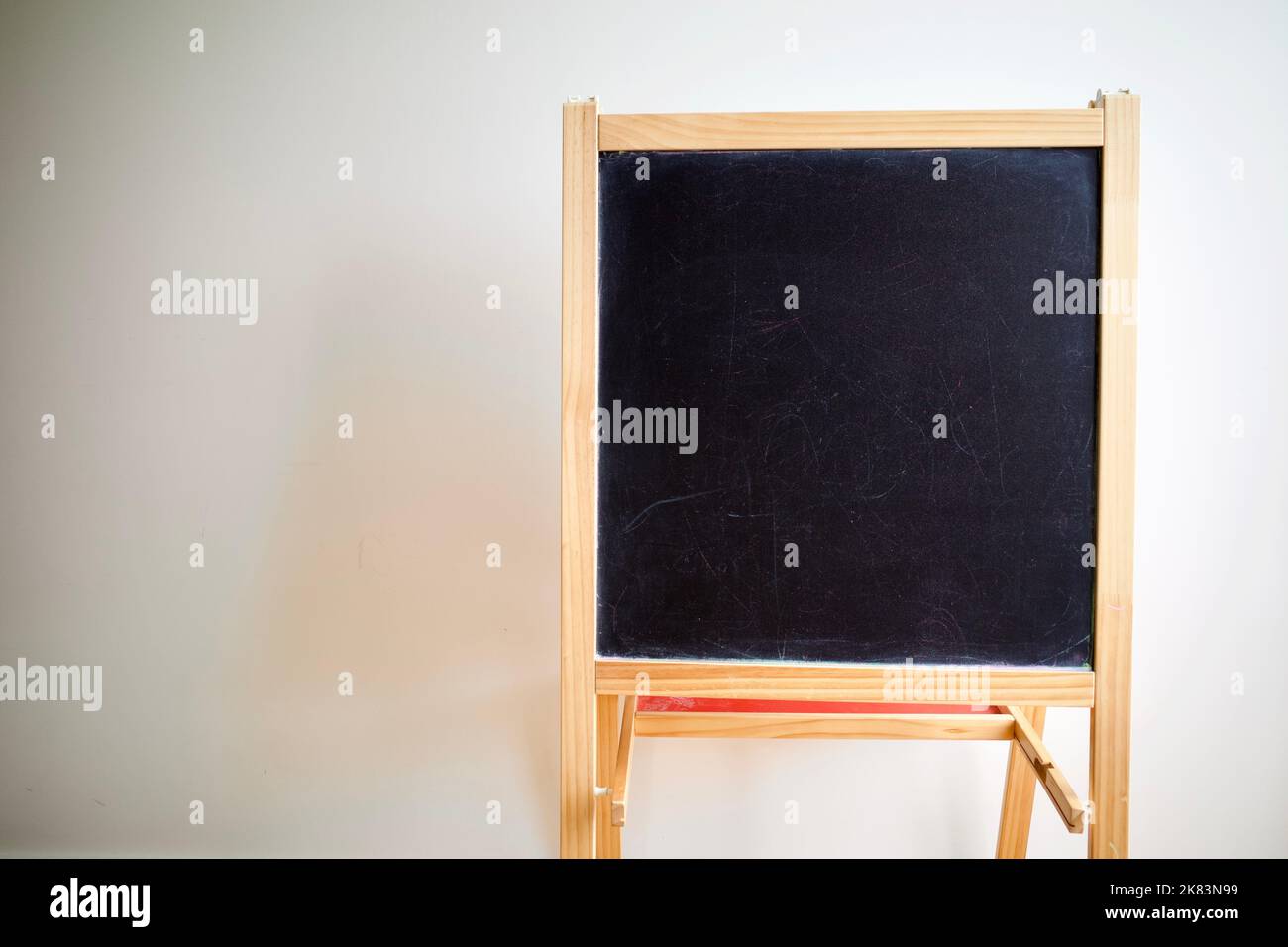An empty black board against white wall Stock Photo