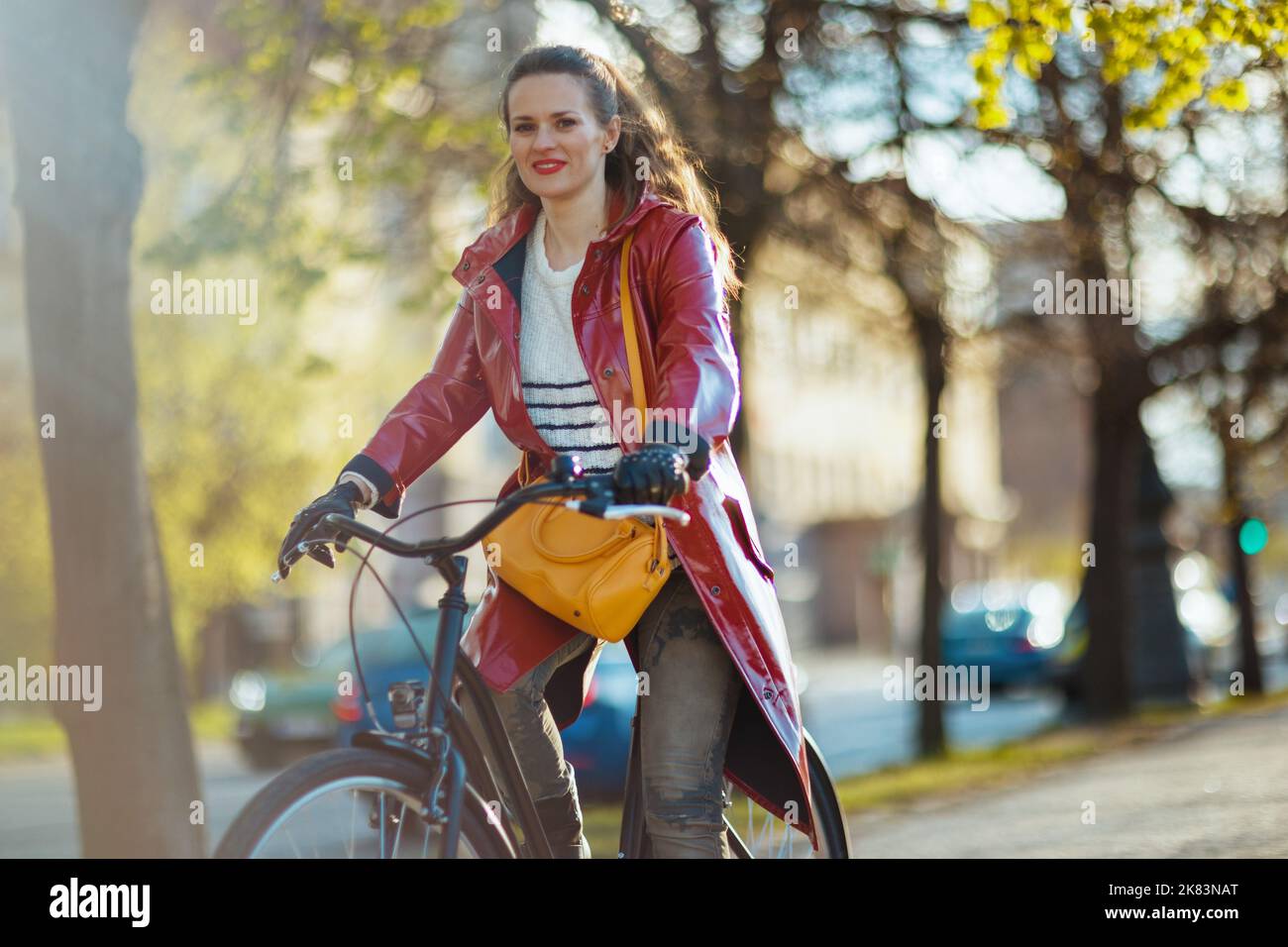 modern woman in red rain coat outdoors in the city riding bicycle Stock ...