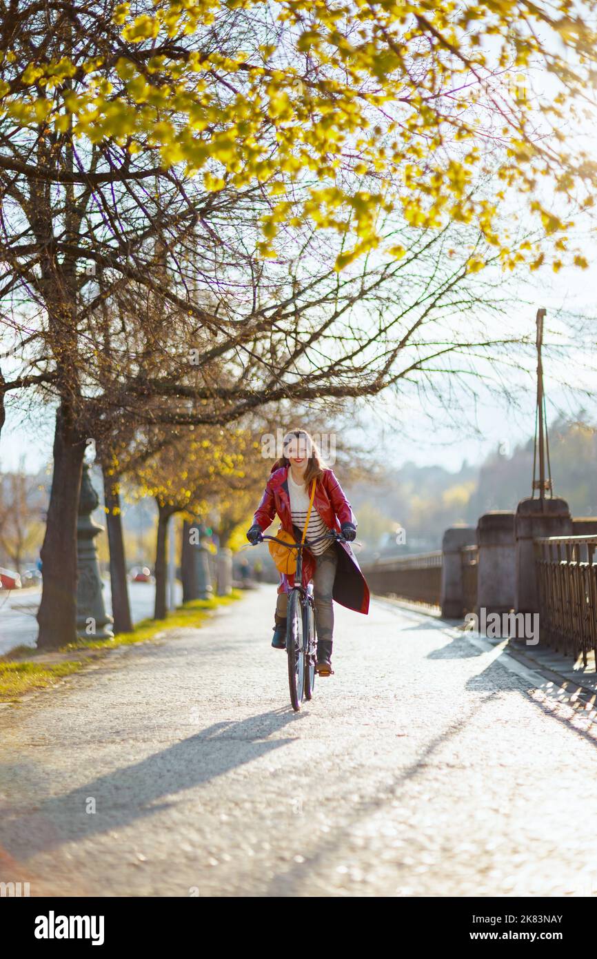 happy elegant middle aged woman in red rain coat outside on the city ...