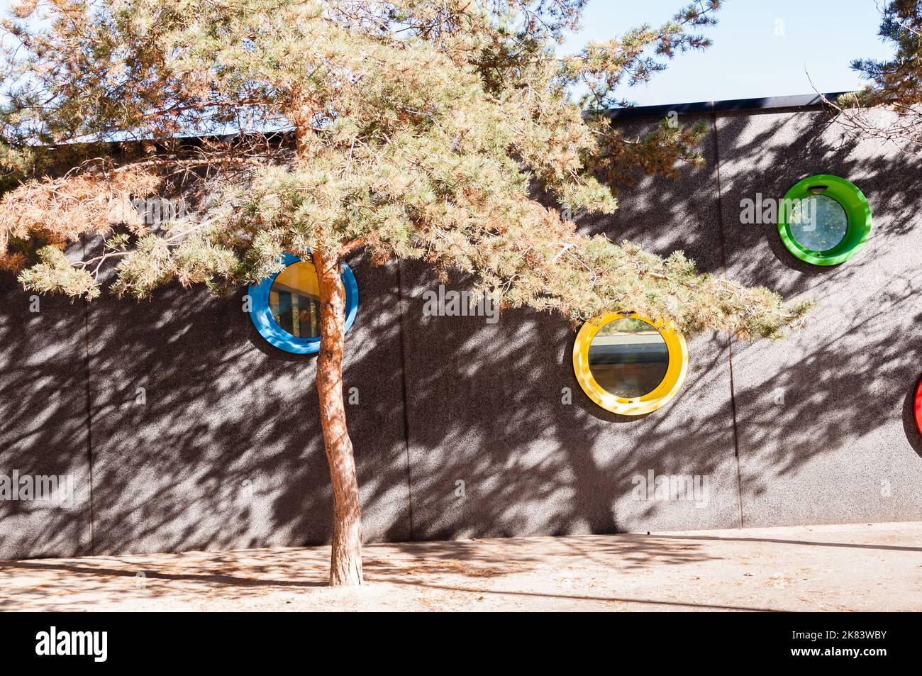 A grey wall with a circular hole through a garden Stock Photo