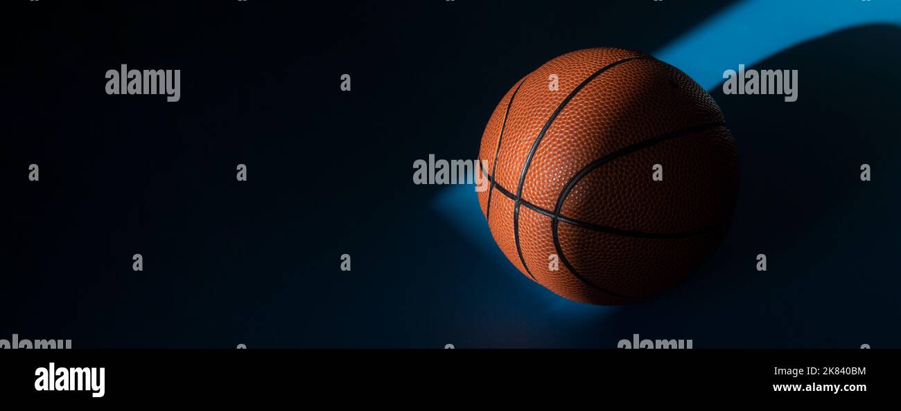 iBrown new basketball ball with natural lighting on blue background. Sport team concept. Horizontal sport theme poster, greeting cards, headers, websi Stock Photo