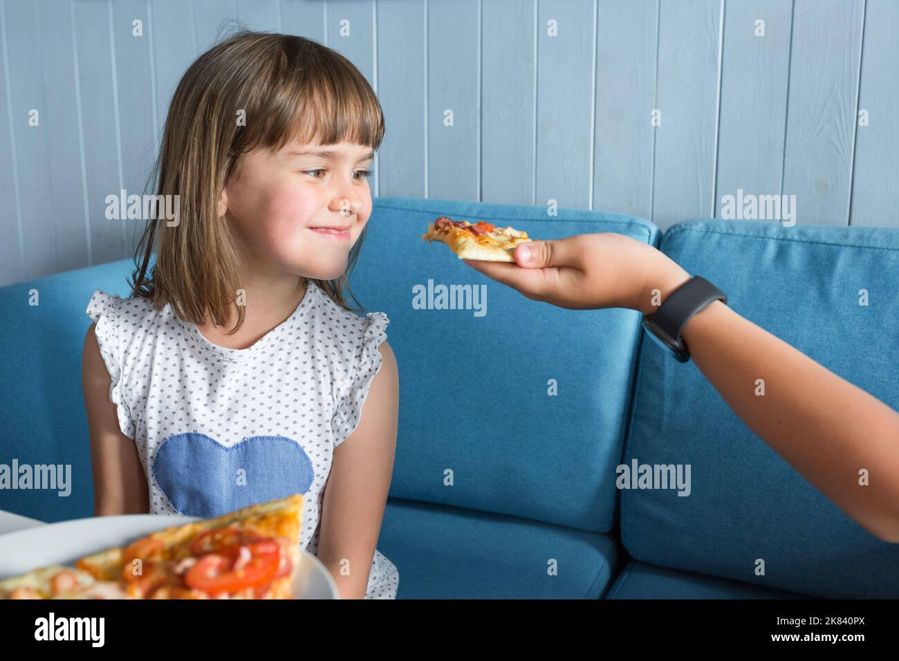 Little beautiful girl looking at a slice of pizza Stock Photo