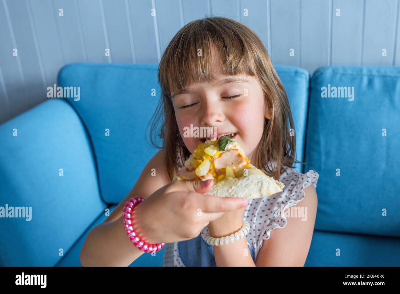 Cute little girl eats pizza. Child has lunch in a cafe, close-up Stock Photo