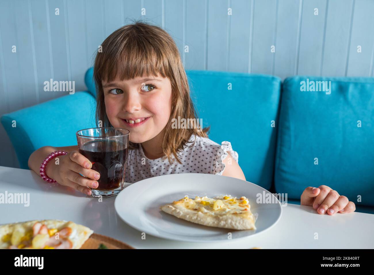 A happy little girl in a restaurant. A child with a cola in his hands Stock Photo