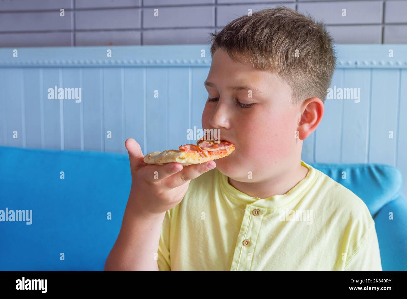 The boy enjoys eating pizza. Concept - Obesity and unhealthy diet Stock Photo