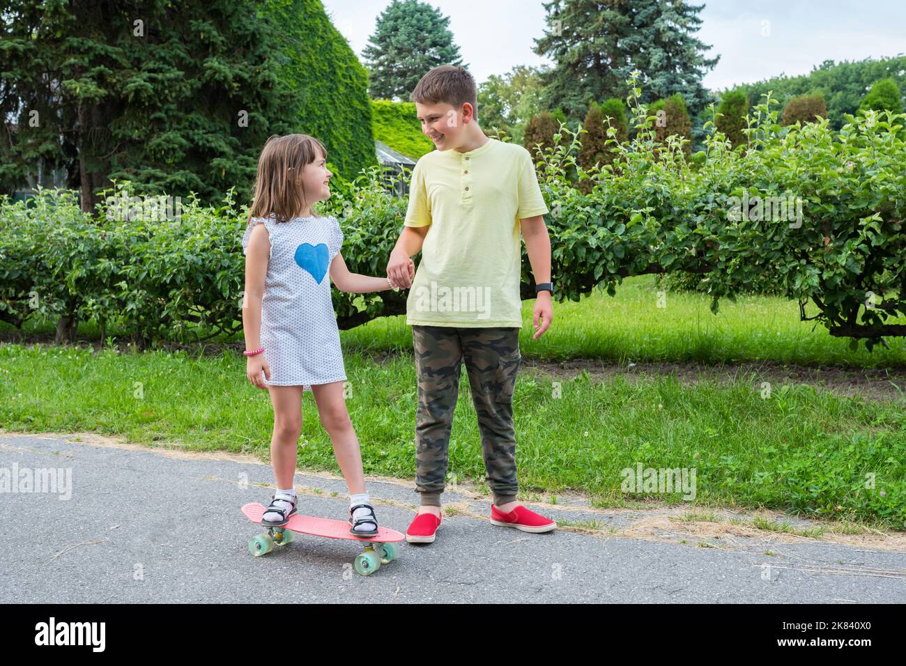 Happy children play in the park and ride on a skateboard Stock Photo Alamy