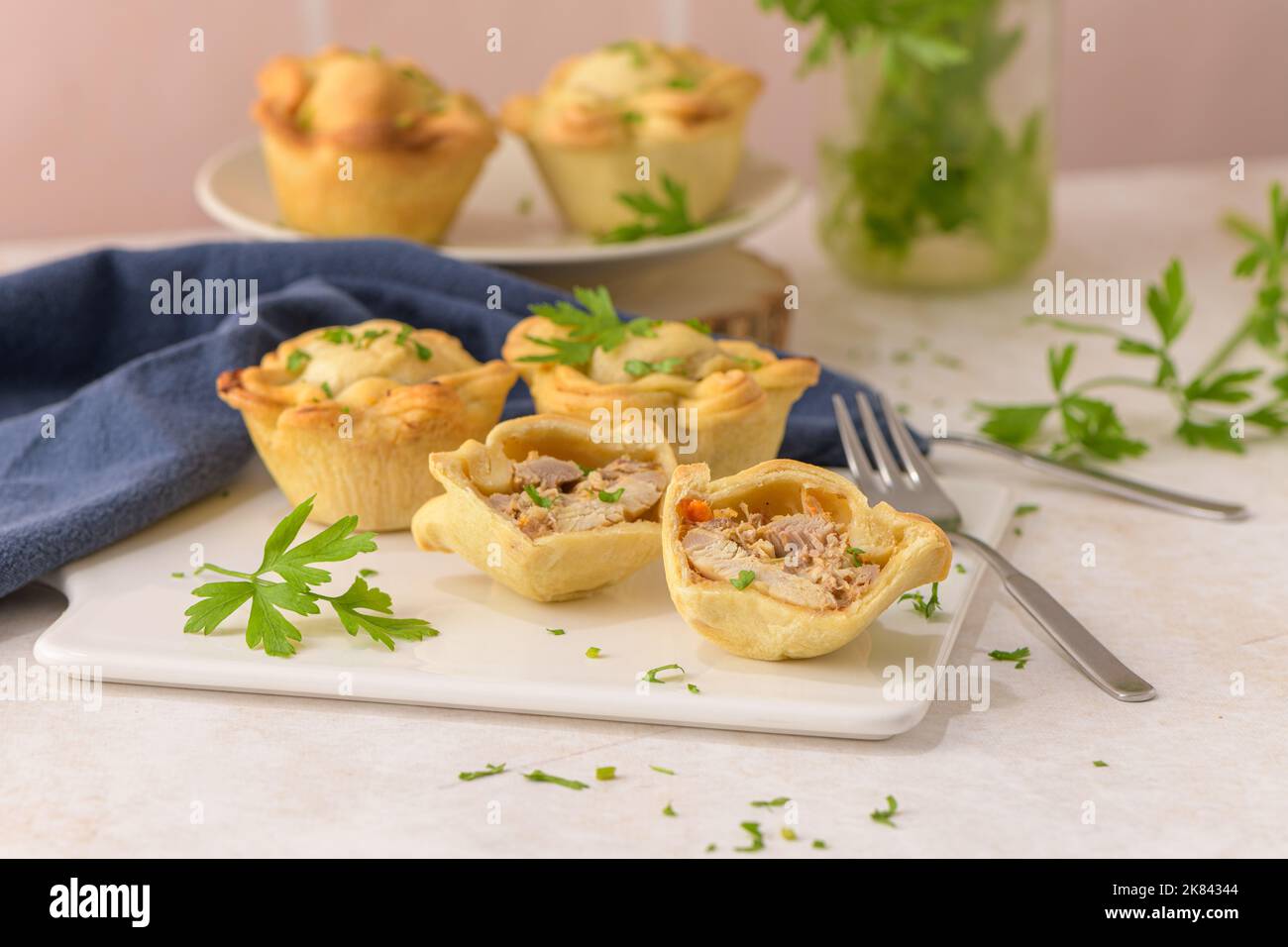 Chicken pies and parsley leaves on white ceramic dishes in a kitchen