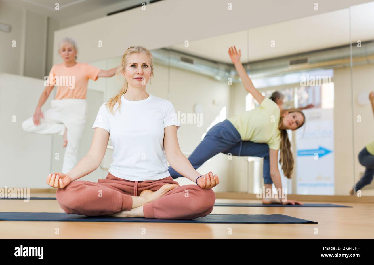 Continuity of generations - family in lotus position doing yoga in gym ...