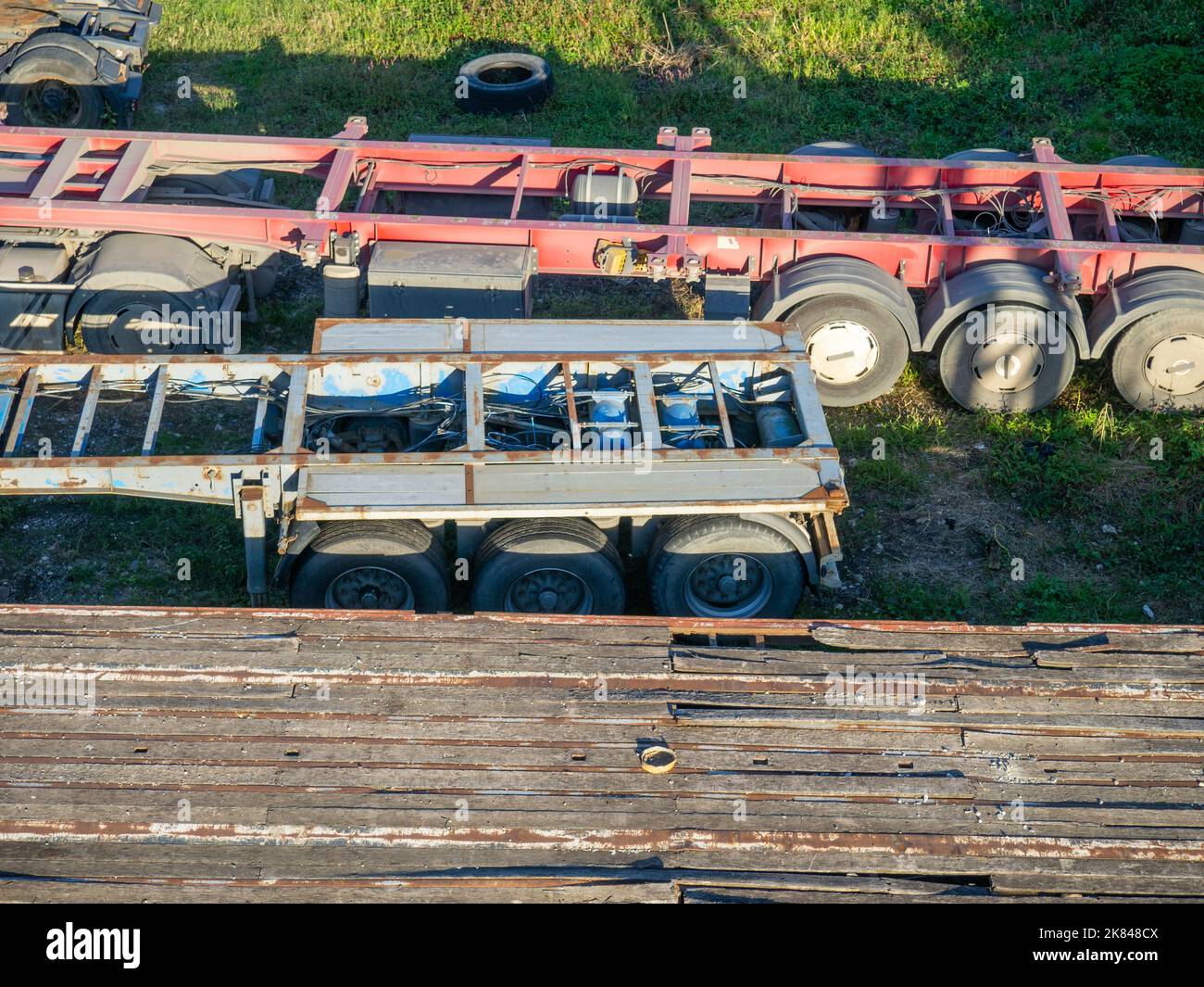 Trucks without trucks are parked. Cars on the grass. Unloaded trucks