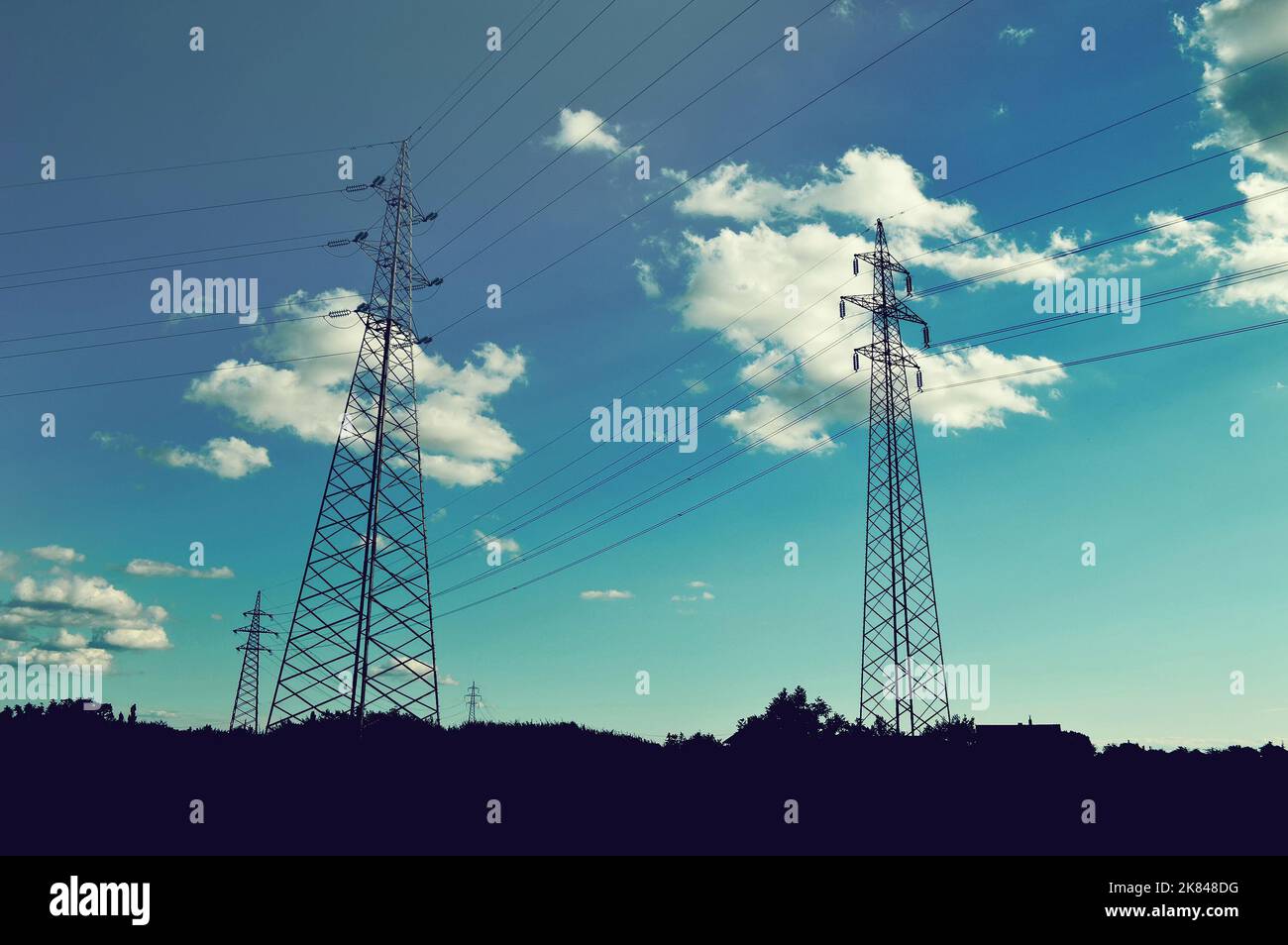 Transmission towers carrying high voltage electric power lines. Silhouettes of electricity pylons in the field Stock Photo