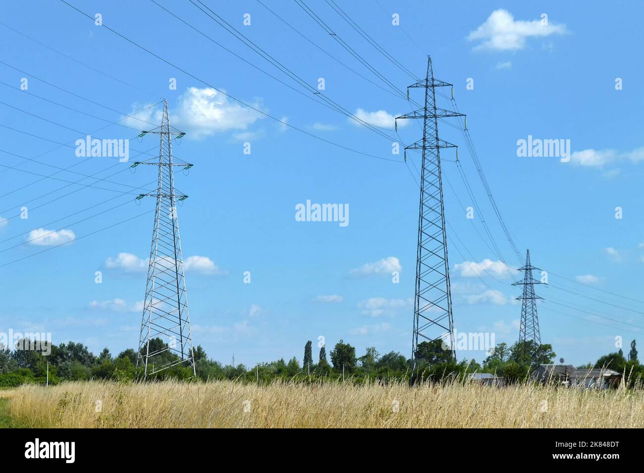 Transmission towers carrying high voltage electric power lines. Electricity pylons in the field Stock Photo