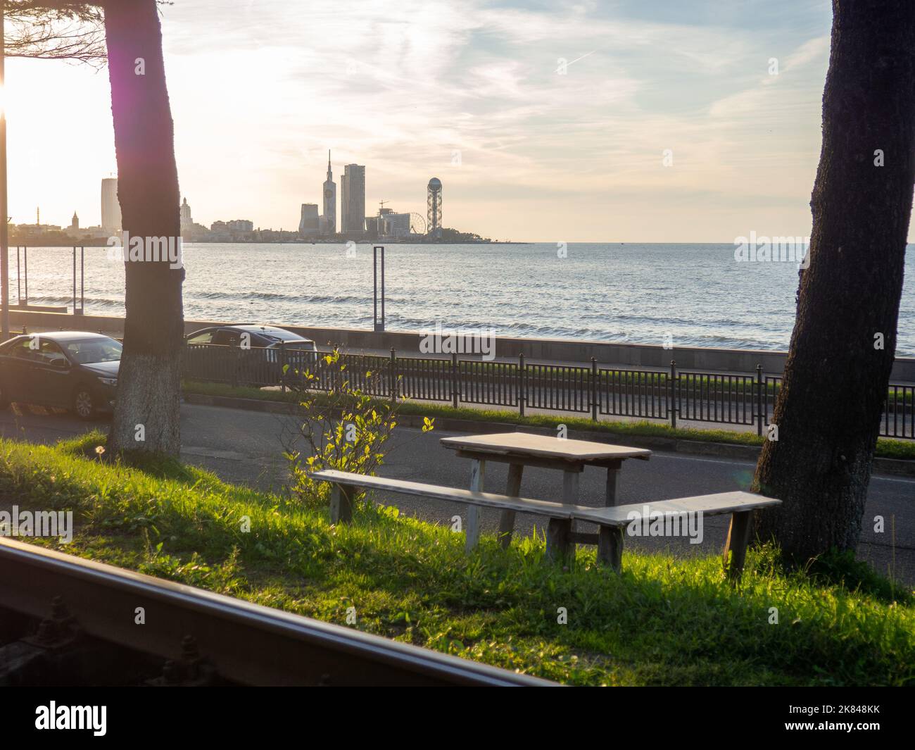 Seats with a table against the backdrop of the sea and the city. Nice place to eat. Sunset over the city. Cozy place Stock Photo