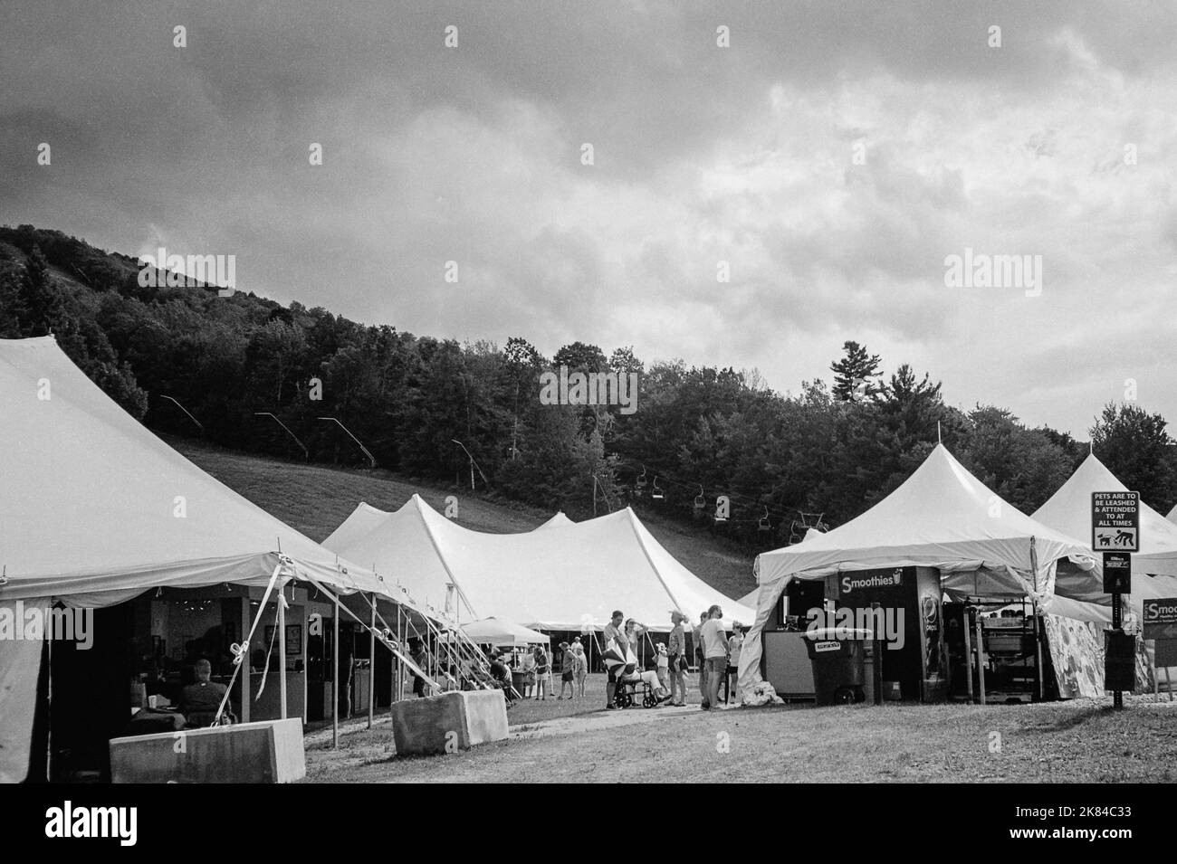 A row of vendor tents below the sky slope with storm clouds above at