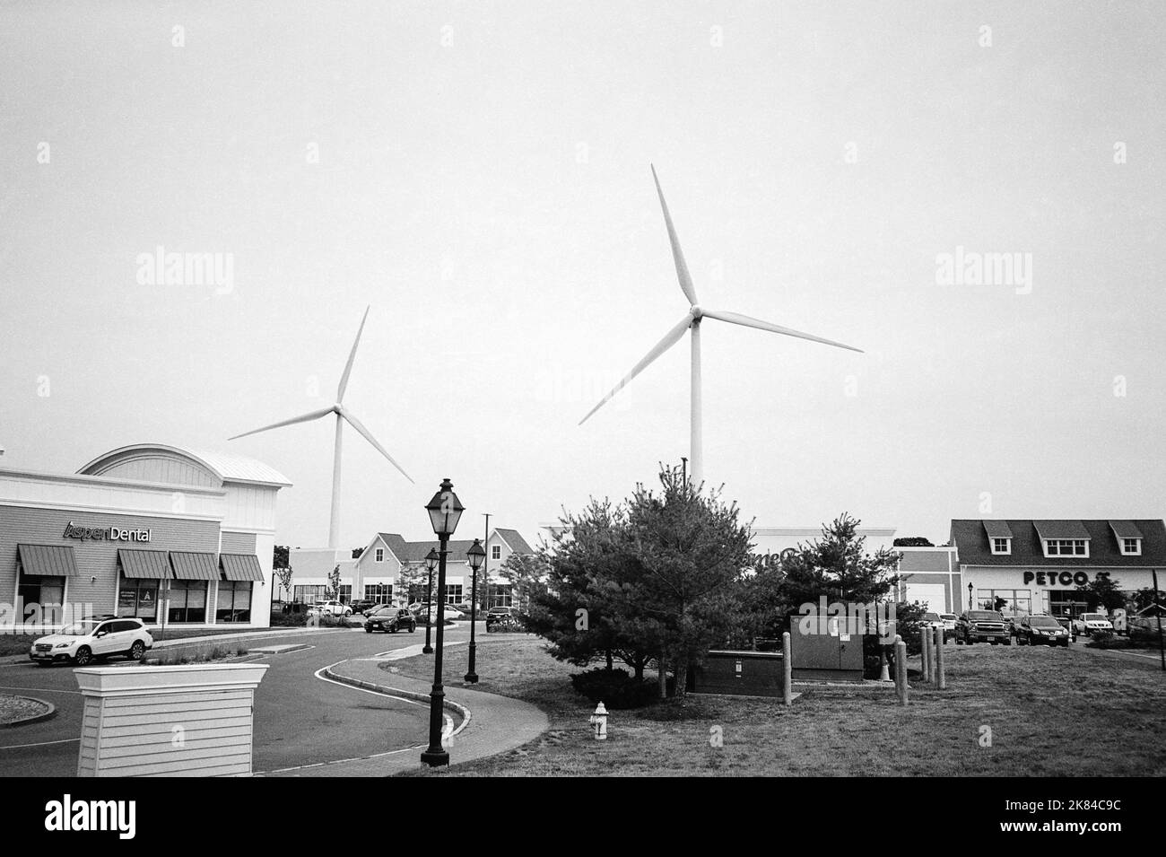 Two large wind turbines spin in the background of a shopping plaza in New Hampshire. Image captured on analog black and white film. Stock Photo