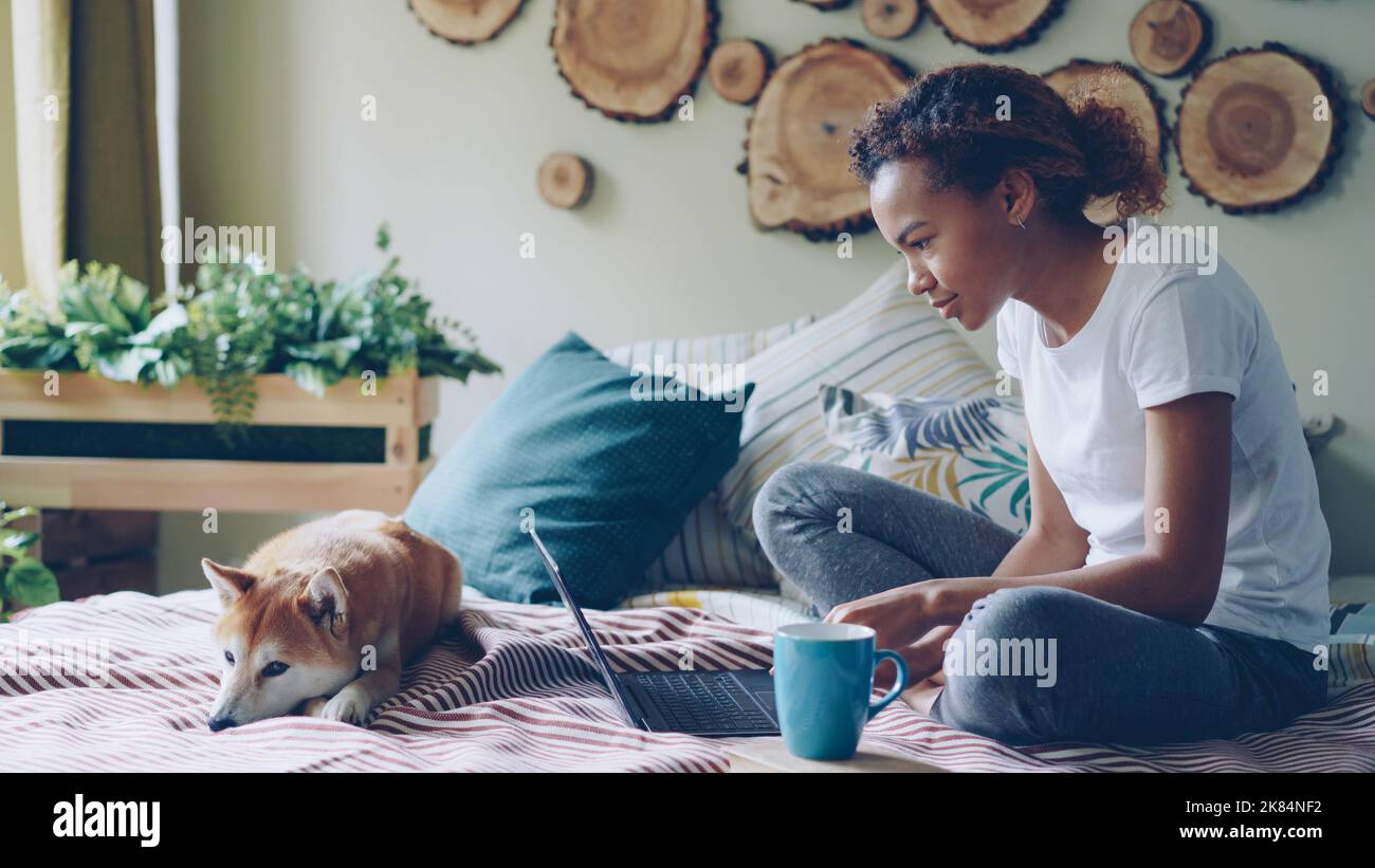 Modern African American girl is using laptop and drinking coffee ...