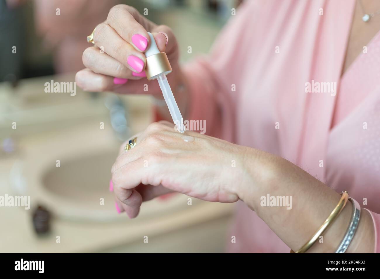 Senior woman applying skin care products in the form of serum for hydration and personal care. Stock Photo