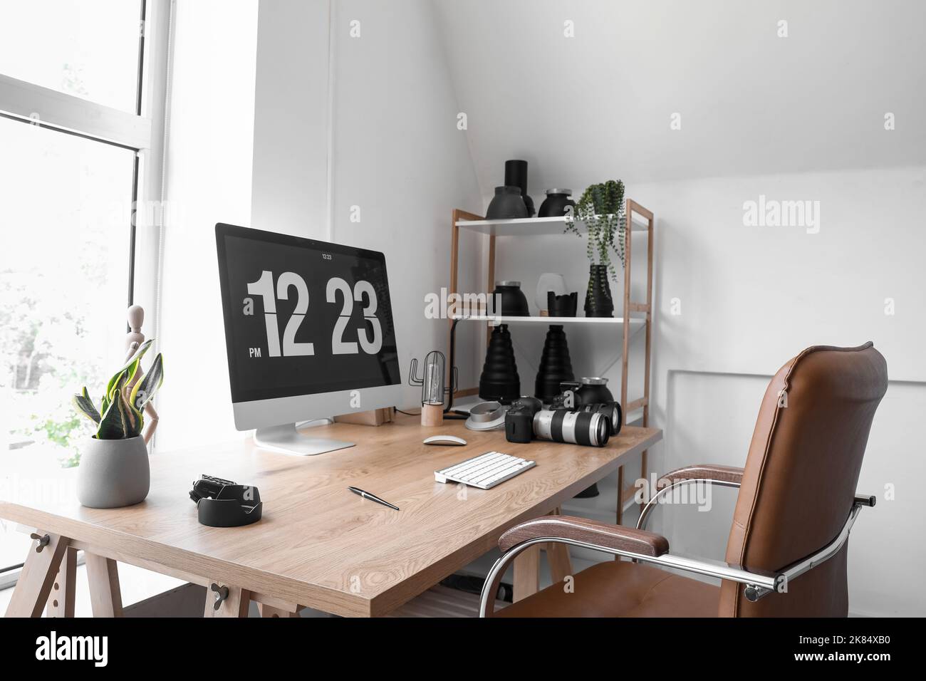 Interior of light office with photographer's workplace, shelving unit