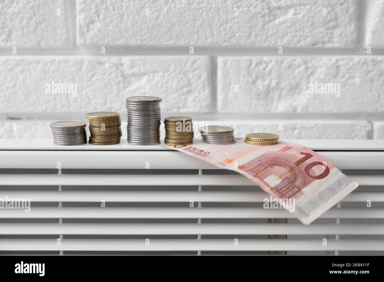Radiator with money near white brick wall, closeup. Heating season ...