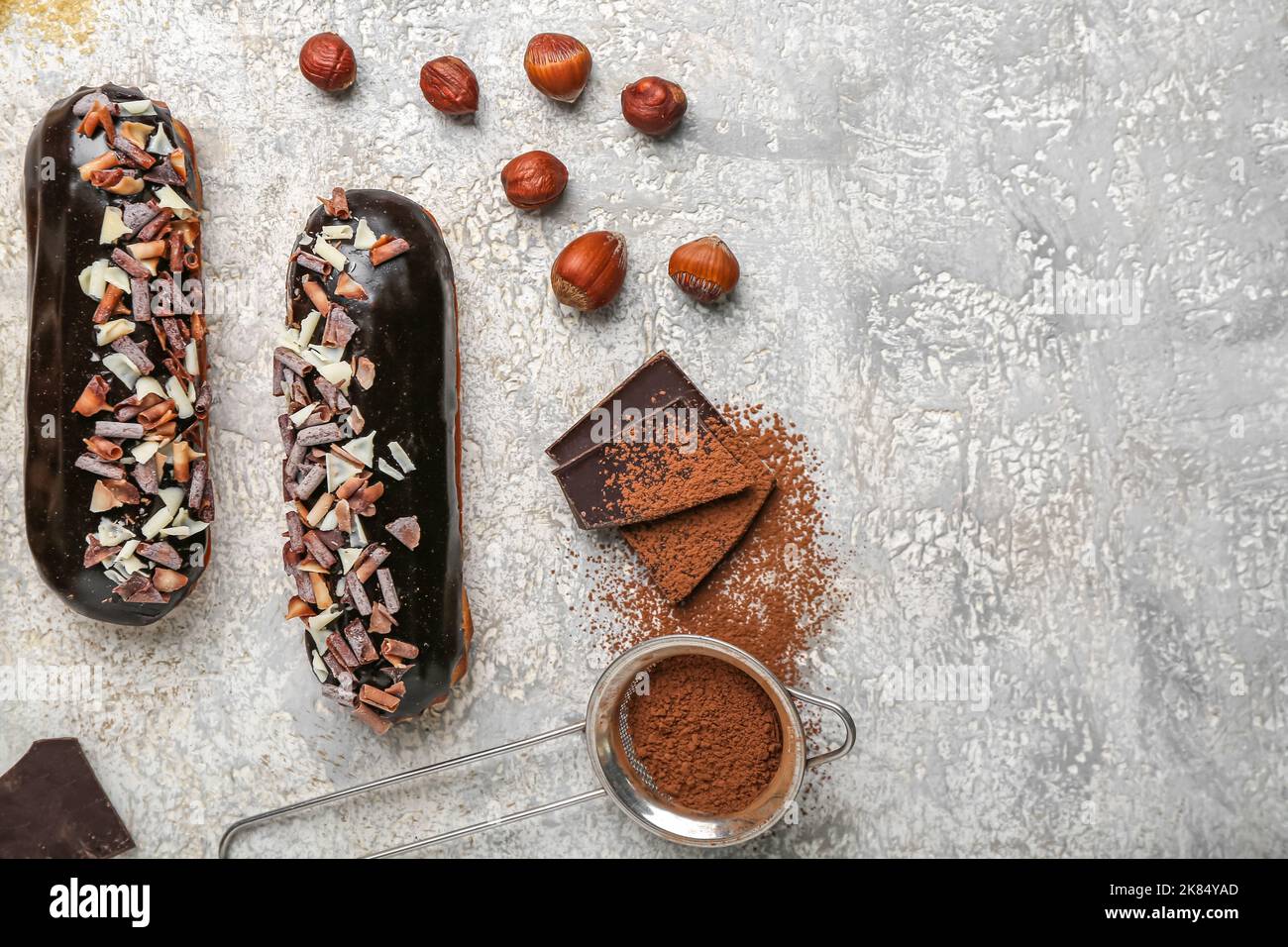Tasty chocolate eclairs and hazelnuts on light background Stock Photo