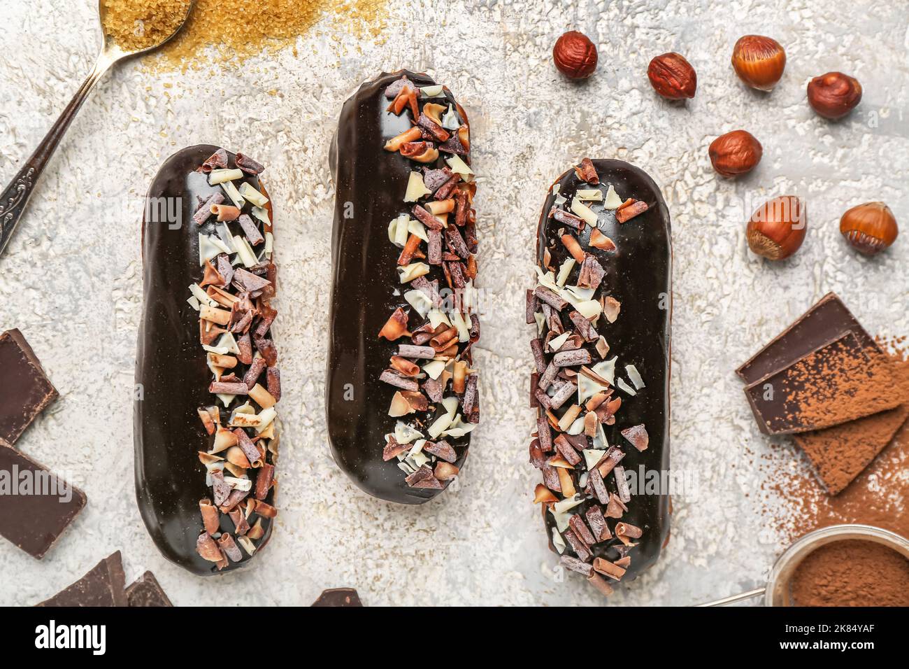 Tasty chocolate eclairs and hazelnuts on light background, closeup Stock Photo