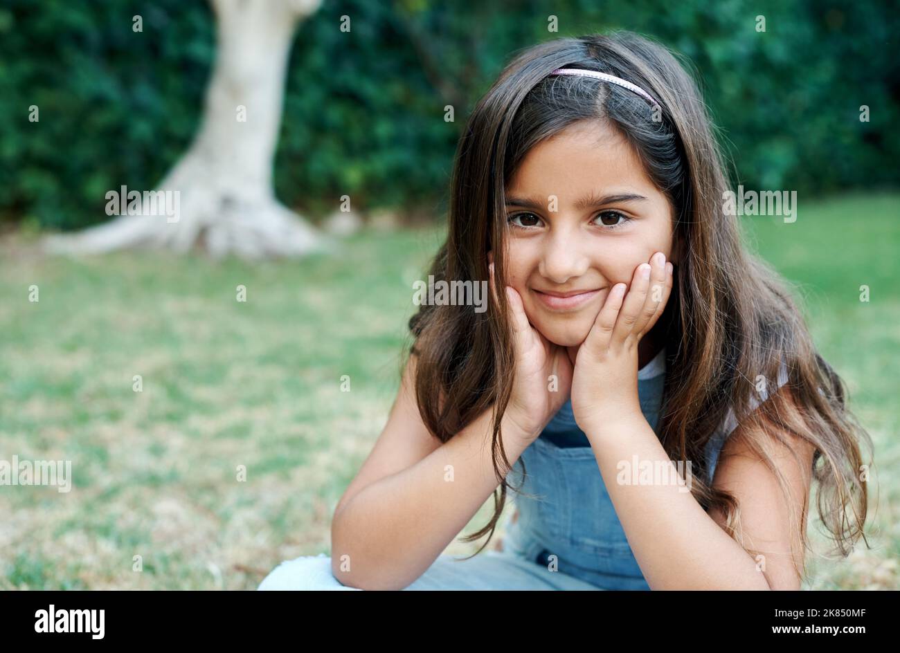I just love being outside. an adorable little girl sitting outside Stock Photo Alamy