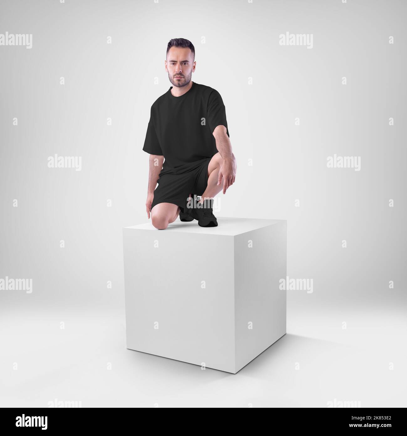Mockup of black men's suit oversized t-shirt on shorts on man on cube. Clothing template for presentations of design, print, pattern. Stock Photo