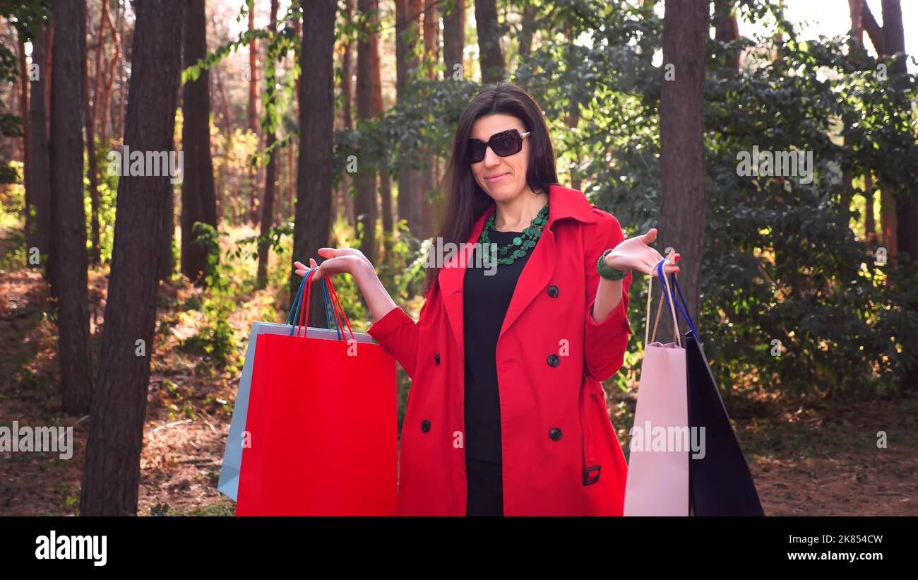 Woman with shopping bags. portrait of attractive woman with colored shopping bags in her hands, in city park. shopping and gifts. delivery or donation concept. High quality photo Stock Photo