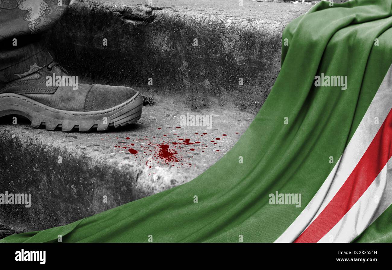 The leg of the military stands on the step next to the flag of Chechen Republic of Ichkeria, the concept of military conflict Stock Photo