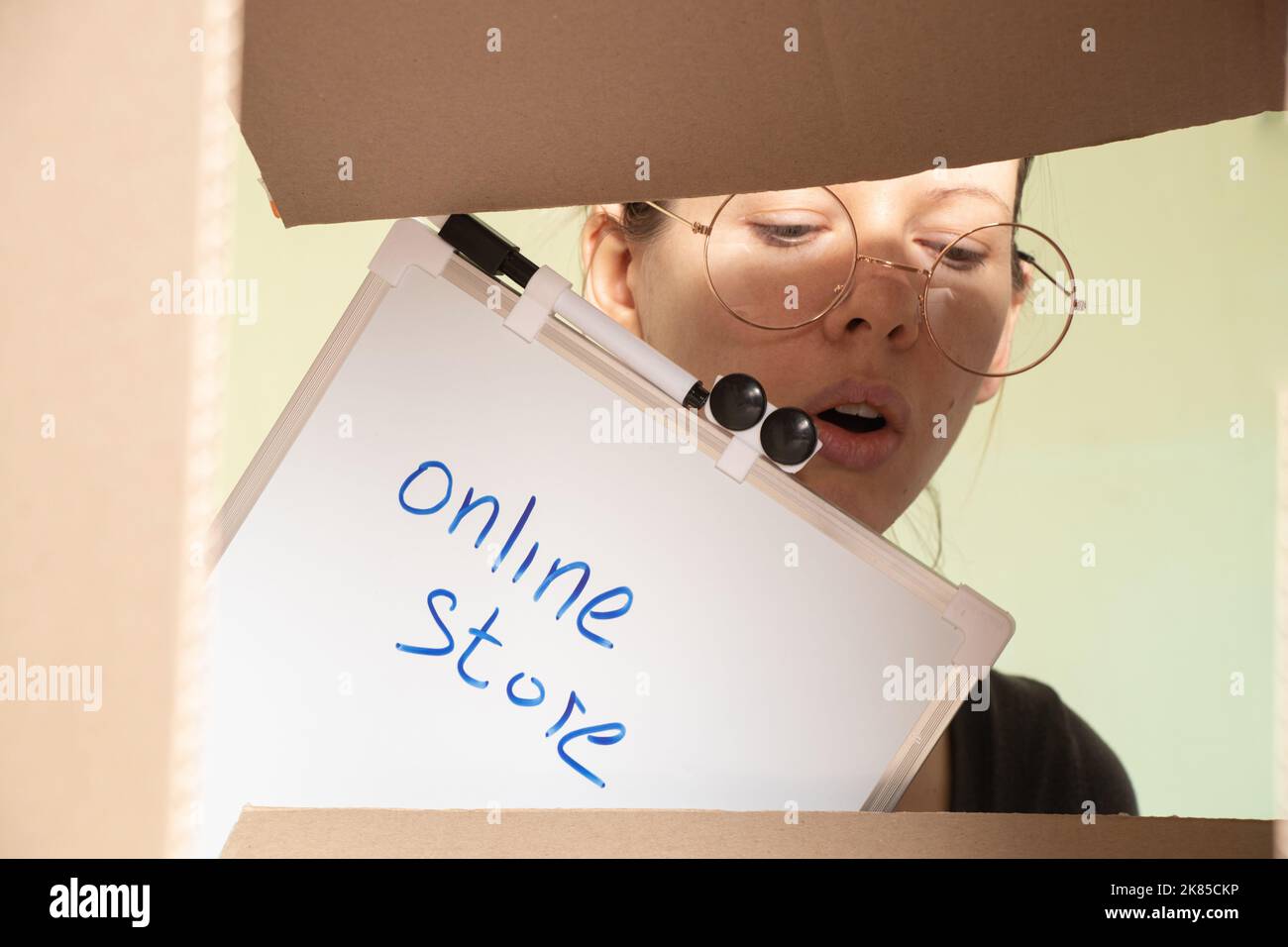 the girl's face looks into a cardboard box with a sign online store