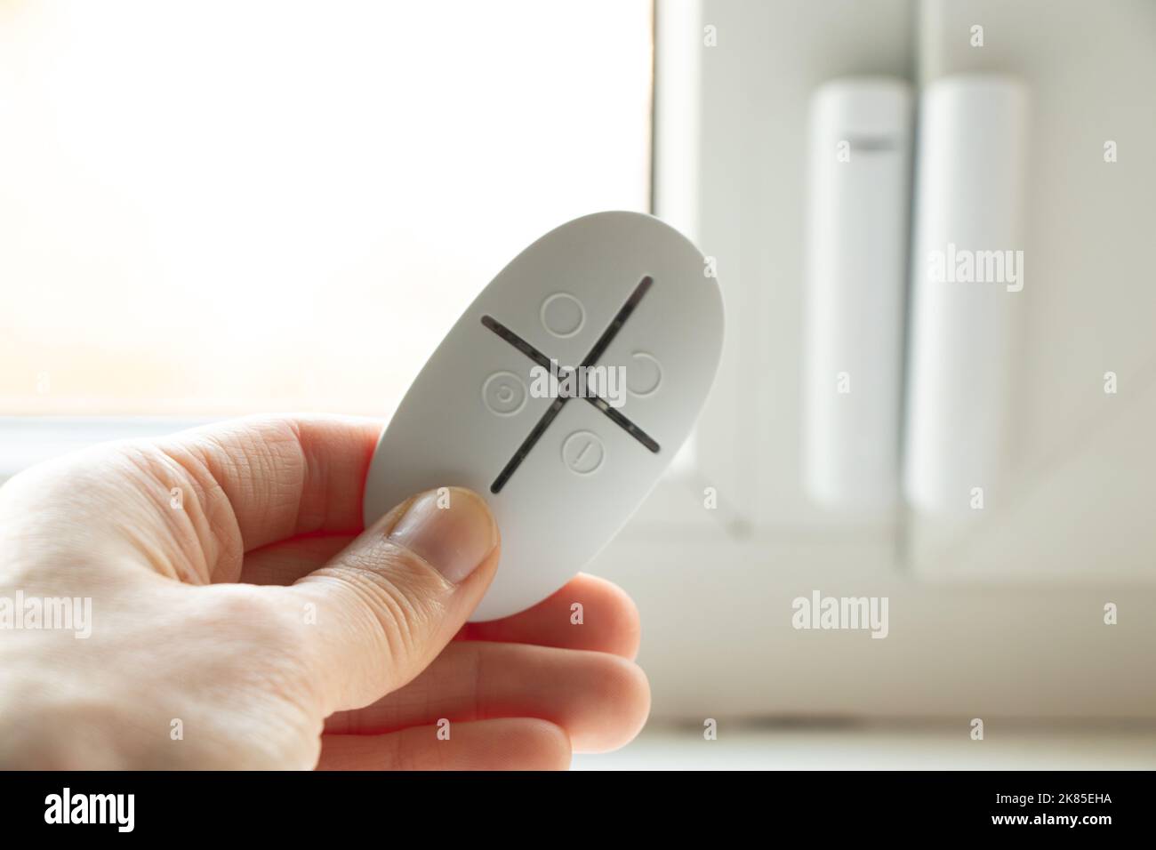 home security system on the windows, an opening sensor and a remote control in the hands of opening and closing, an alarm remote control Stock Photo