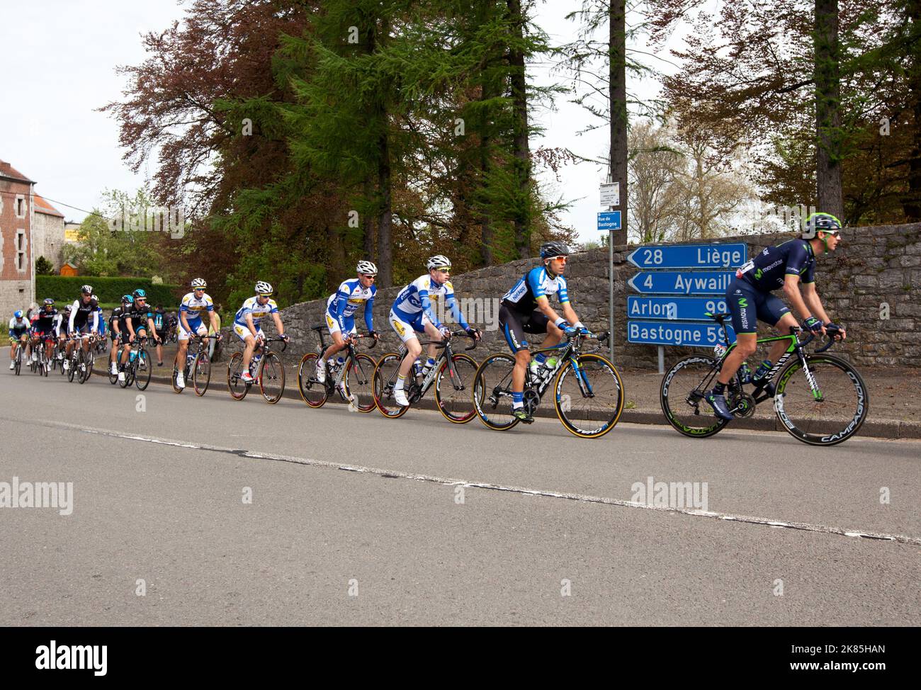 The peloton rolls past Chateau D'Harze where a sign gives a hopeful 59 Km to Bastogne Stock Photo