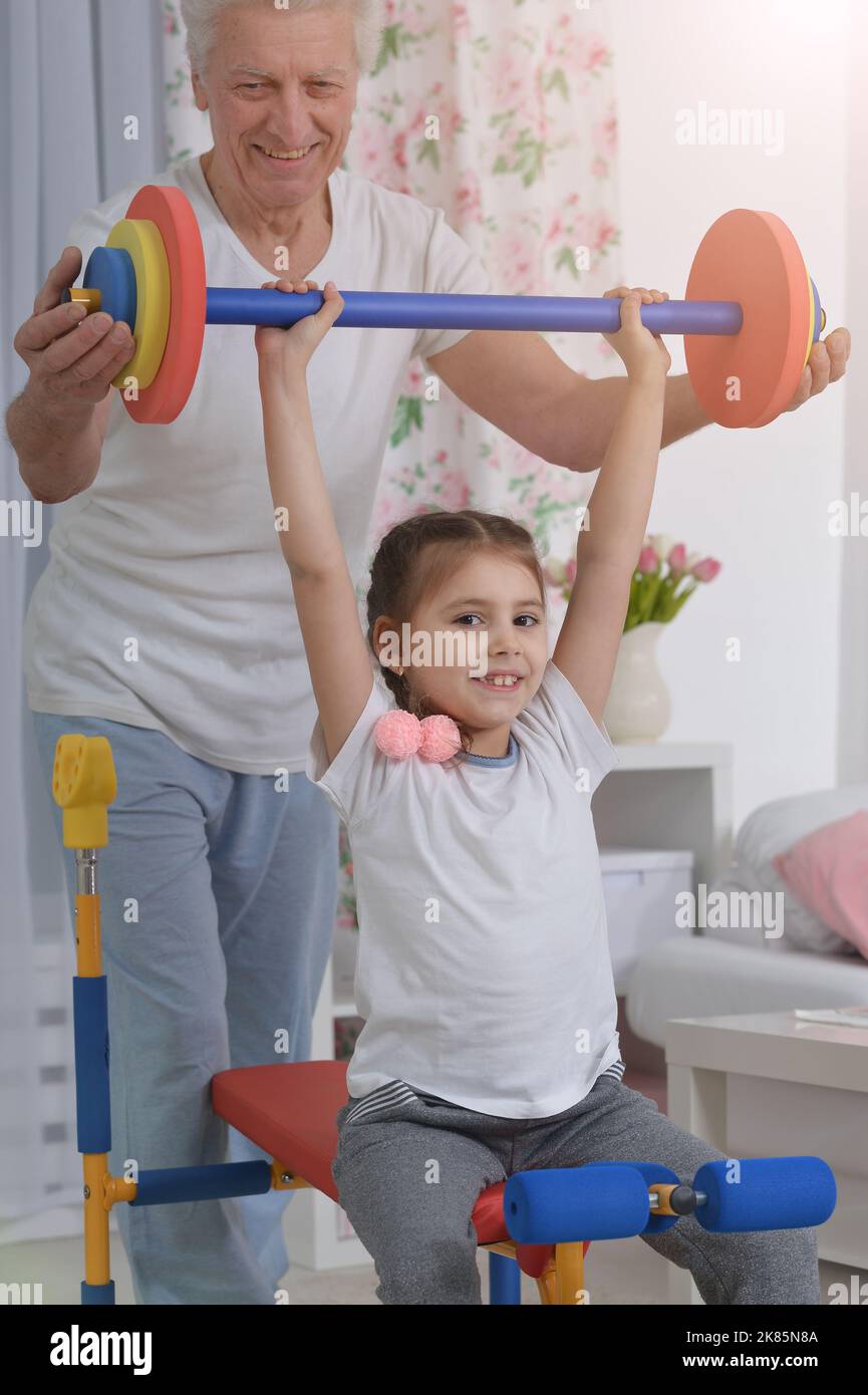 Grandfather and his granddaughter are training in the room Stock Photo
