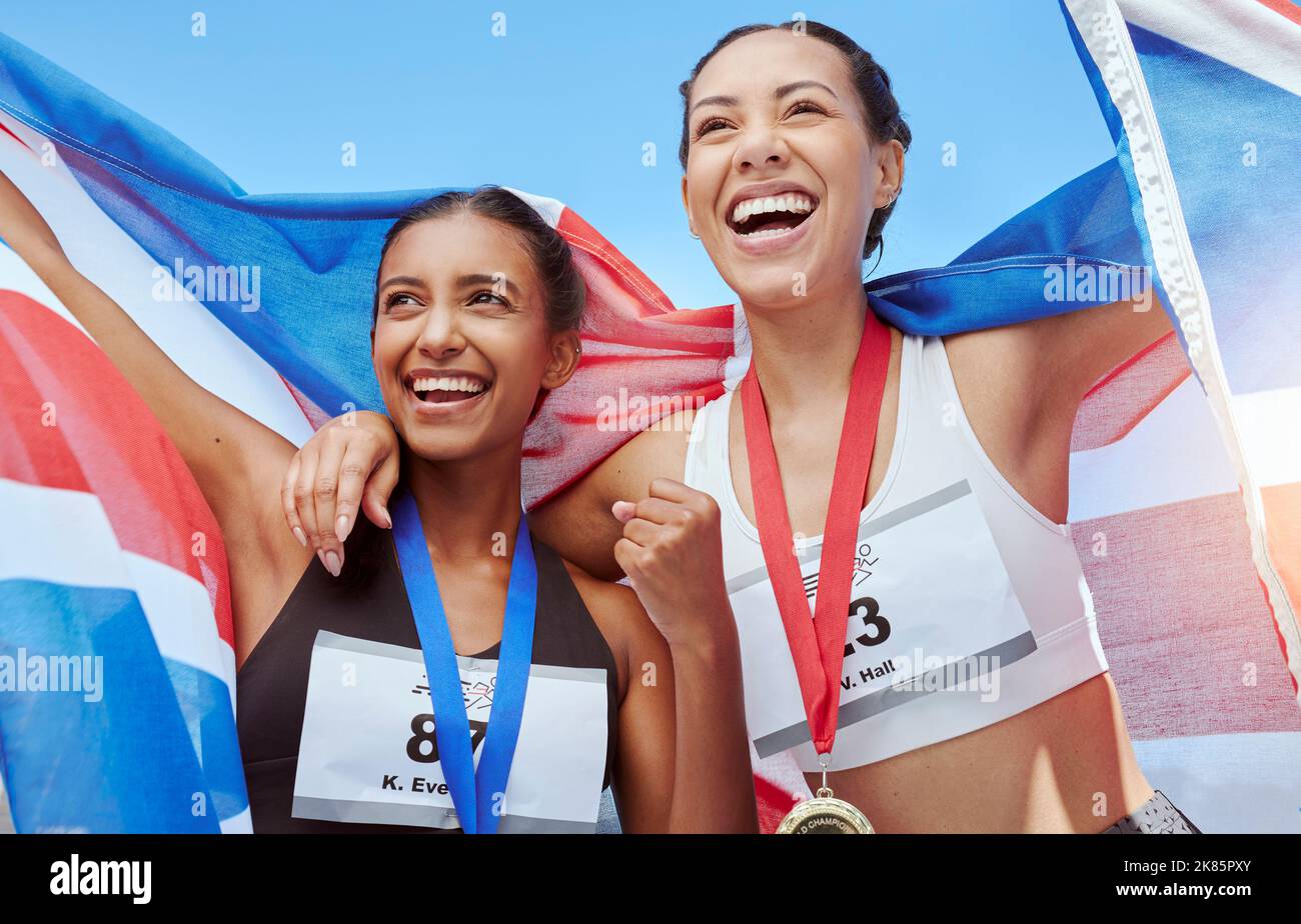 Success, women and running team with a flag in celebration of winners medals achievement at a sports event. Fitness, British and happy athlete runners Stock Photo